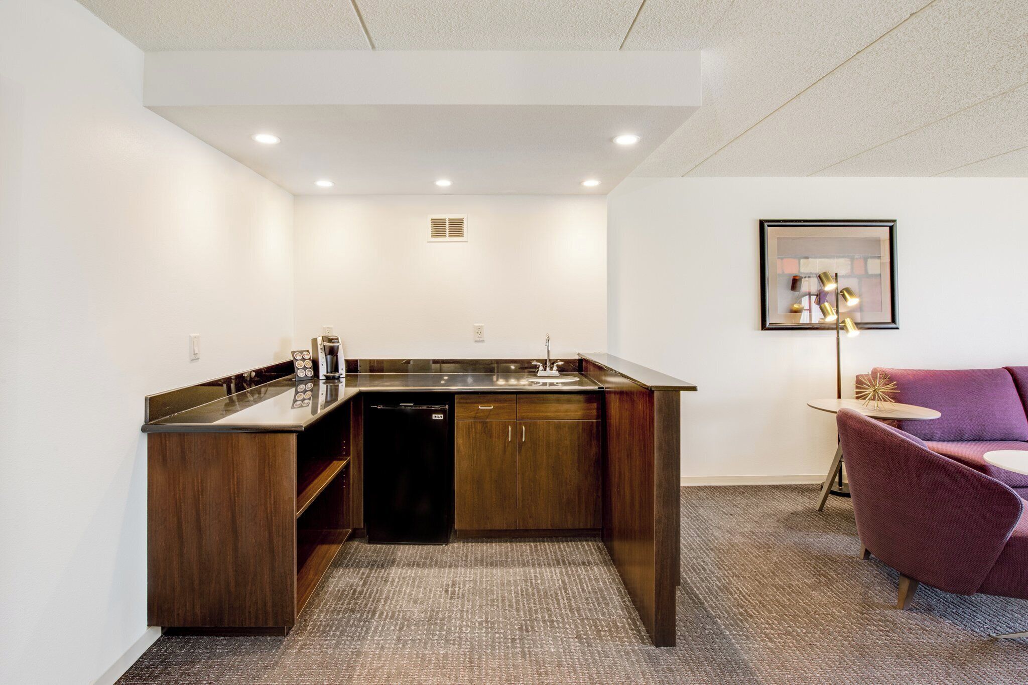 A compact kitchen with a built-in dishwasher, a sink, and a coffee machine.