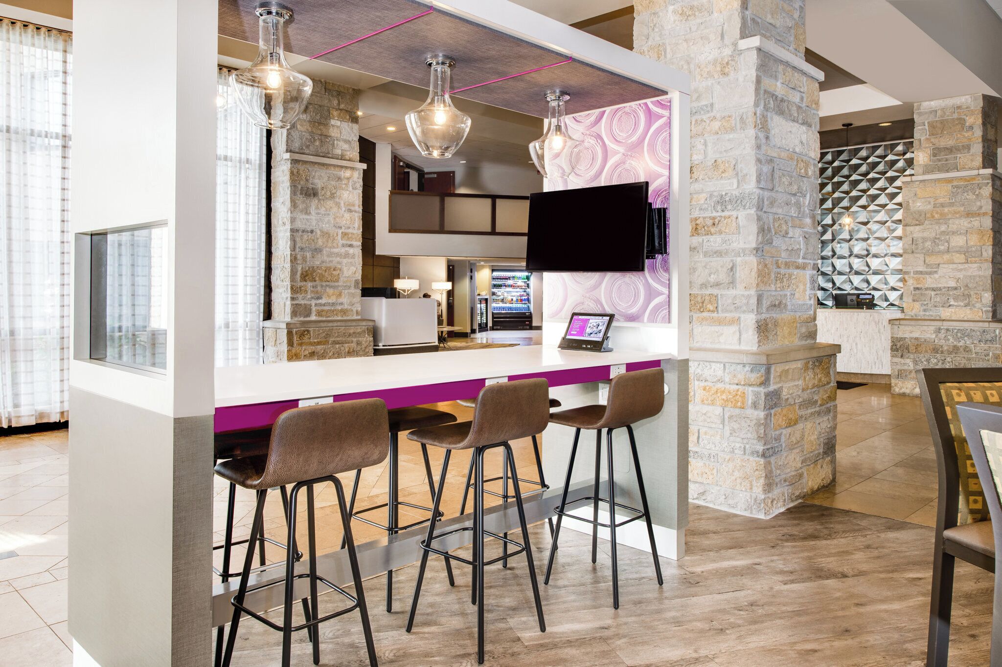 Un área de bar moderna con una pared de acento de piedra, taburetes y luces colgantes.