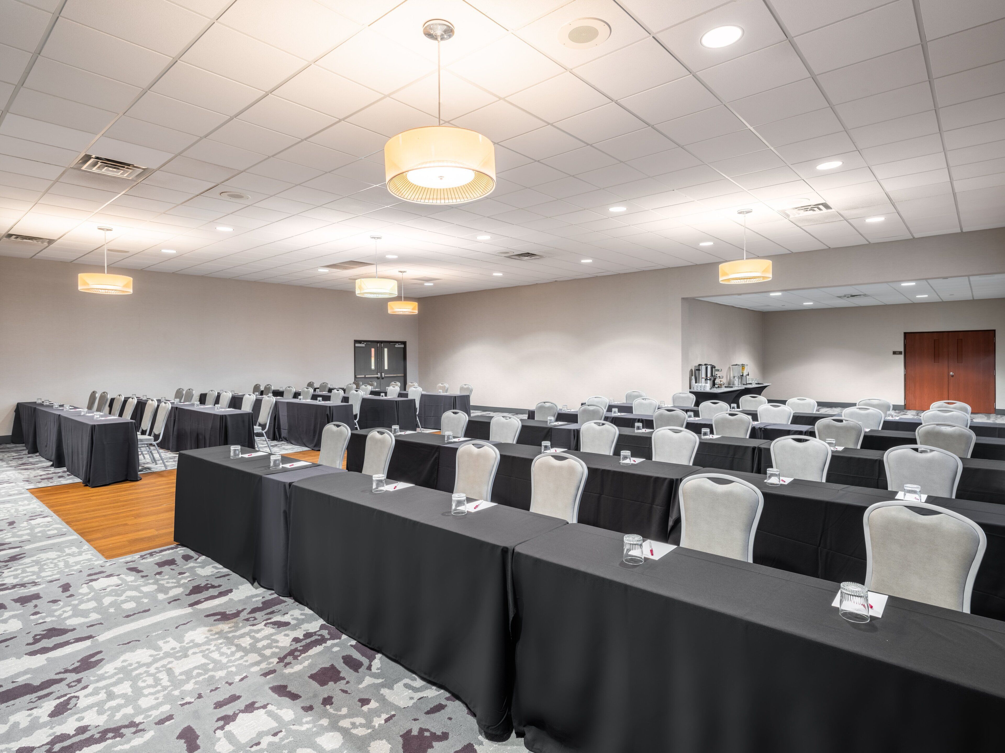 A conference room with rows of tables and chairs, equipped with nameplates and water glasses.