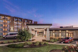 A hotel entrance with a covered walkway, a parking area, and a building with multiple floors. - Crowne Plaza Milwaukee Airport by IHG (Milwaukee)