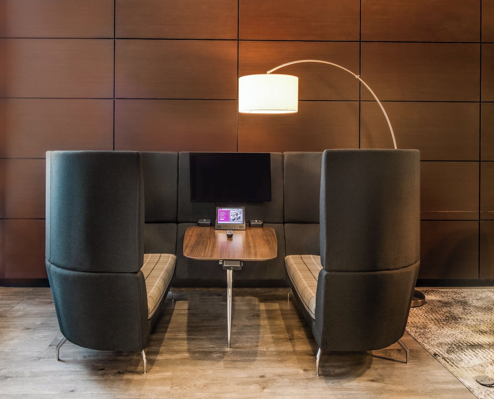 A modern seating area with a flat-screen TV, a small wooden table, and a unique lighting fixture.