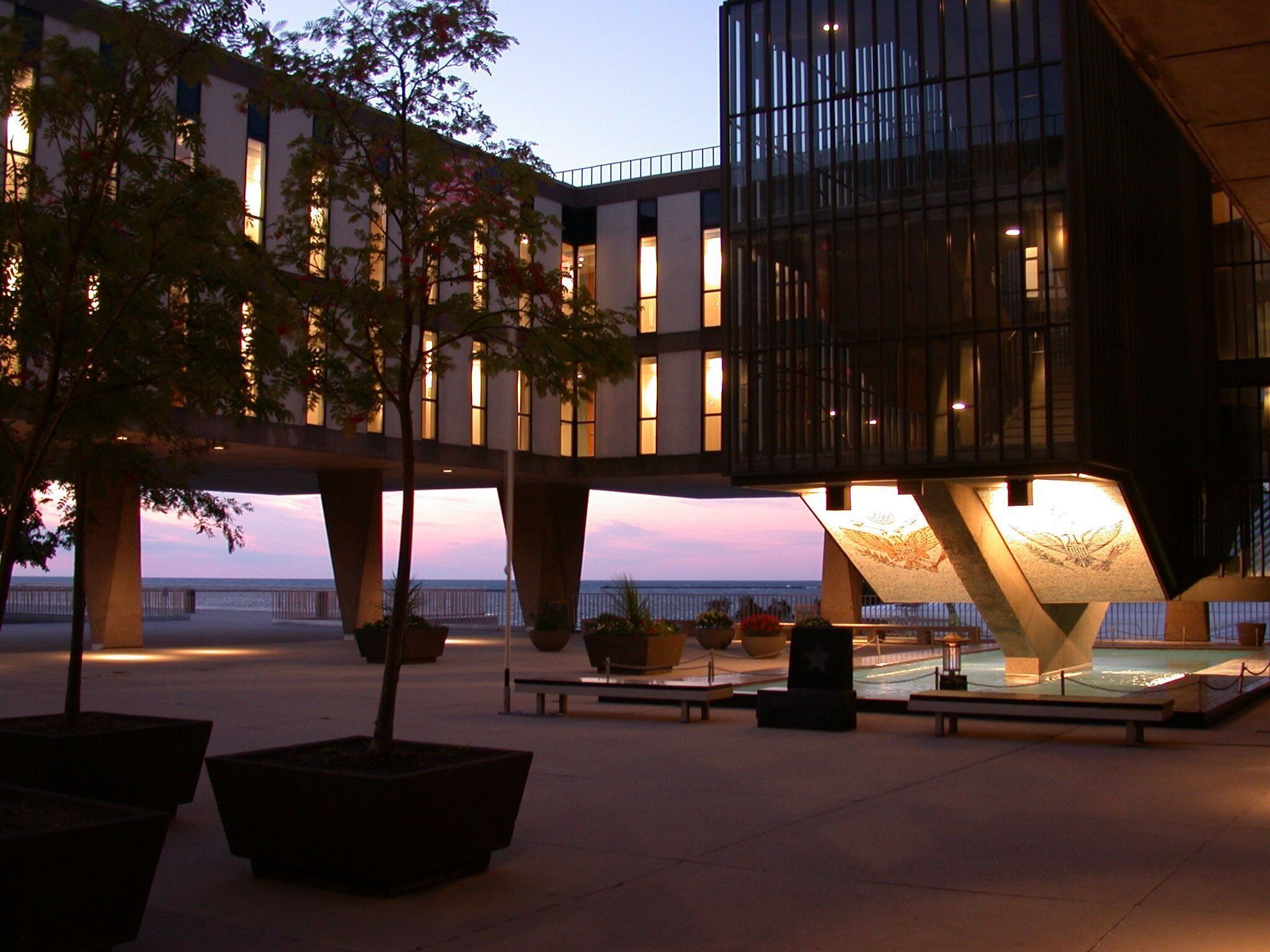 Un bâtiment moderne avec une piscine et des plantes en pot au premier plan.