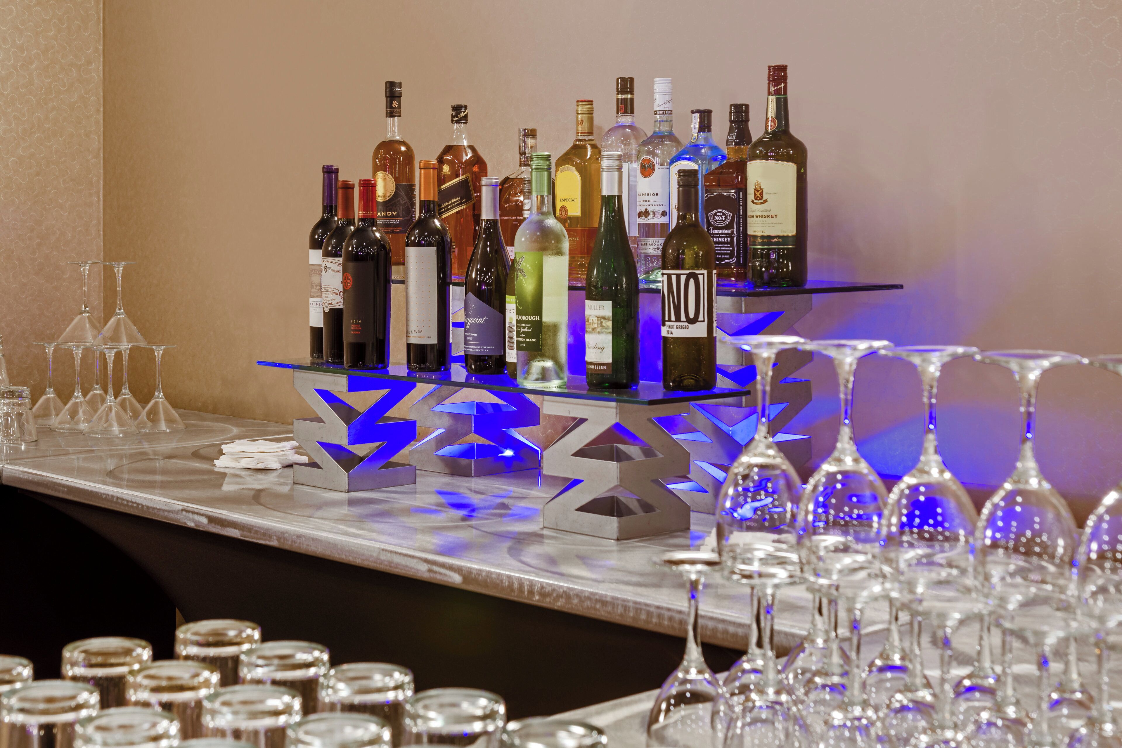 Zona de bar con varias botellas de alcohol y copas de vino vacías.