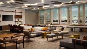 Un hall d’hôtel moderne doté d’un grand espace salon, d’un bar et de grandes fenêtres offrant une vue sur la campagne.