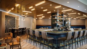 Un espace bar moderne doté d’un long comptoir, de tabourets et de différents types de sièges, notamment des tables et des chaises.
