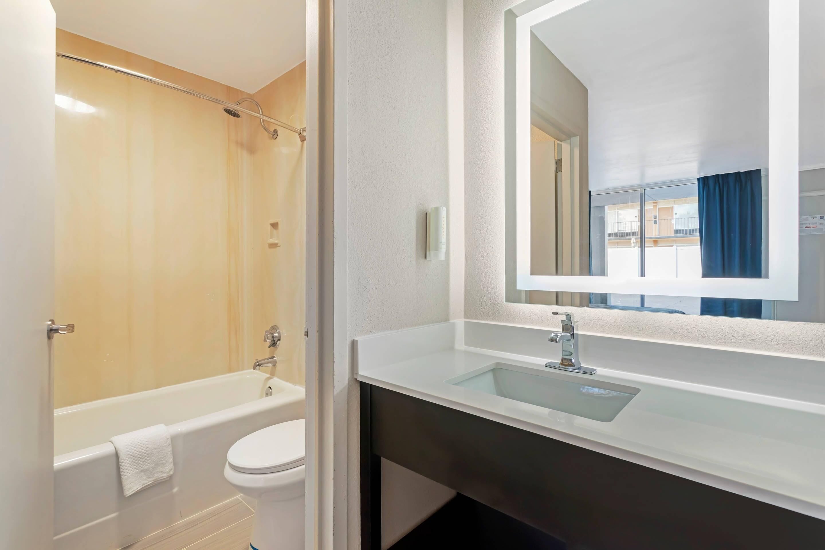 A bathroom with a bathtub, toilet, and a large mirror above a sink.