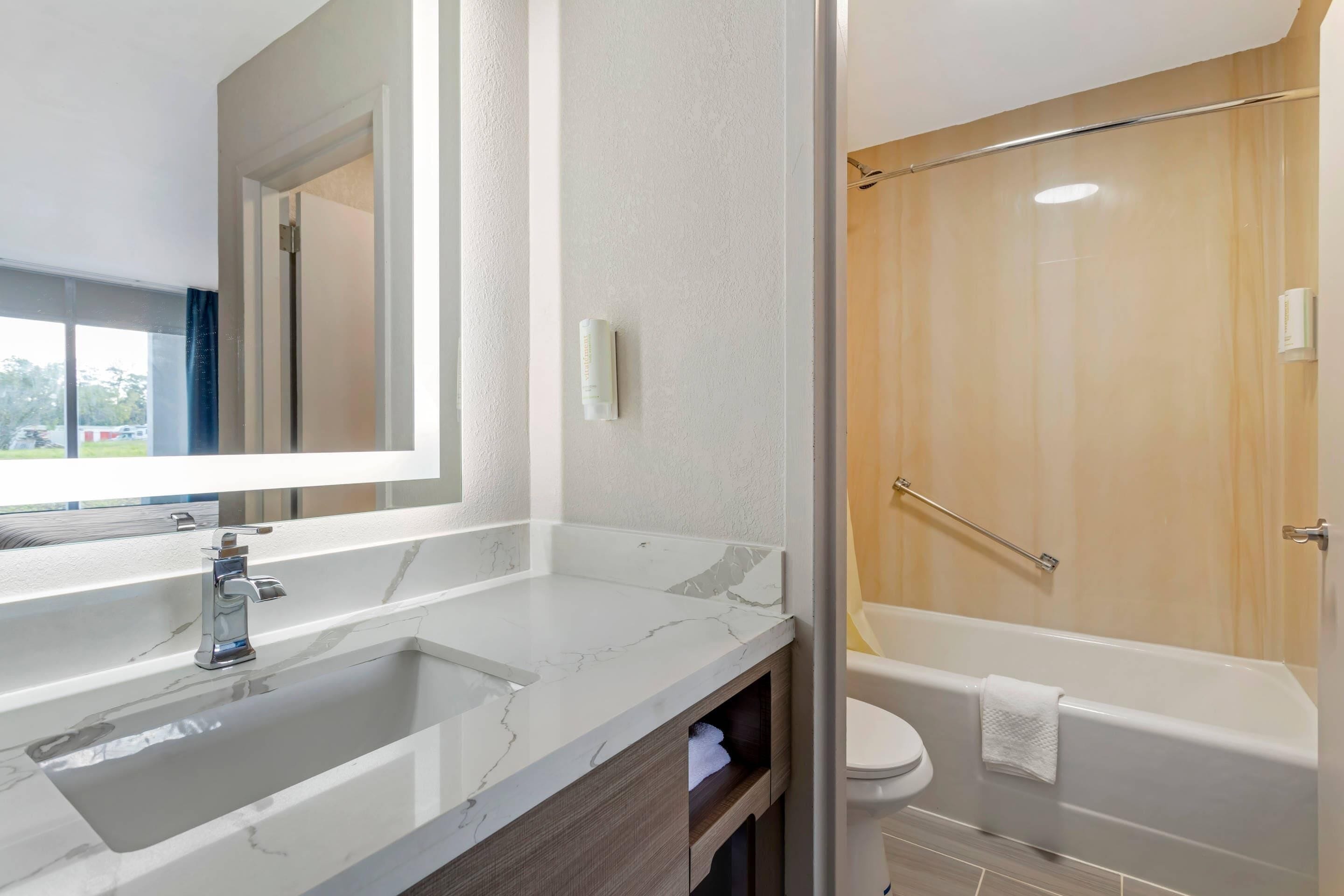 A bathroom with a marble sink, a mirror, a toilet, and a bathtub.