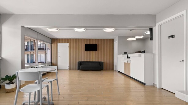 A modern reception area with a flat-screen TV, a reception desk, and a seating area with a table and chairs.