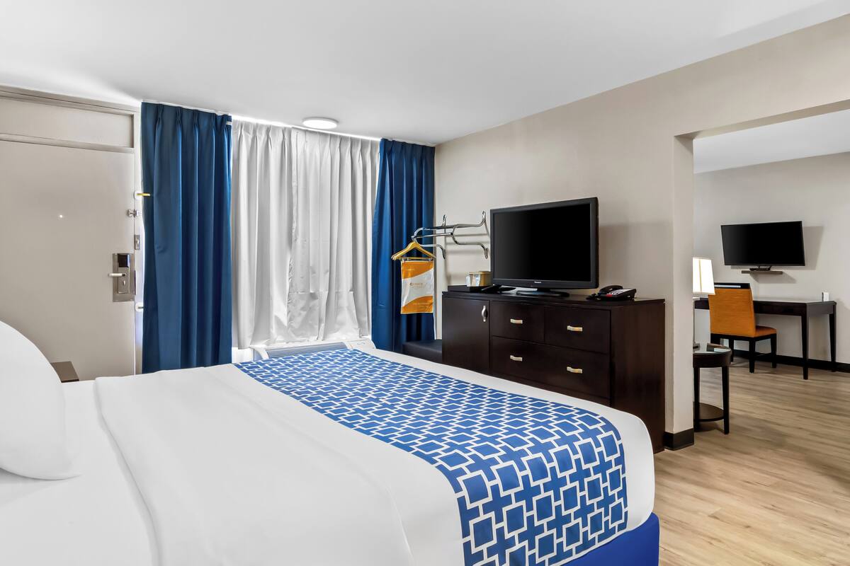 A hotel room with a bed, a desk, a television, and a chair.