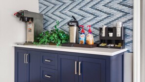A kitchen counter with a coffee machine, a thermos, and a dispenser.