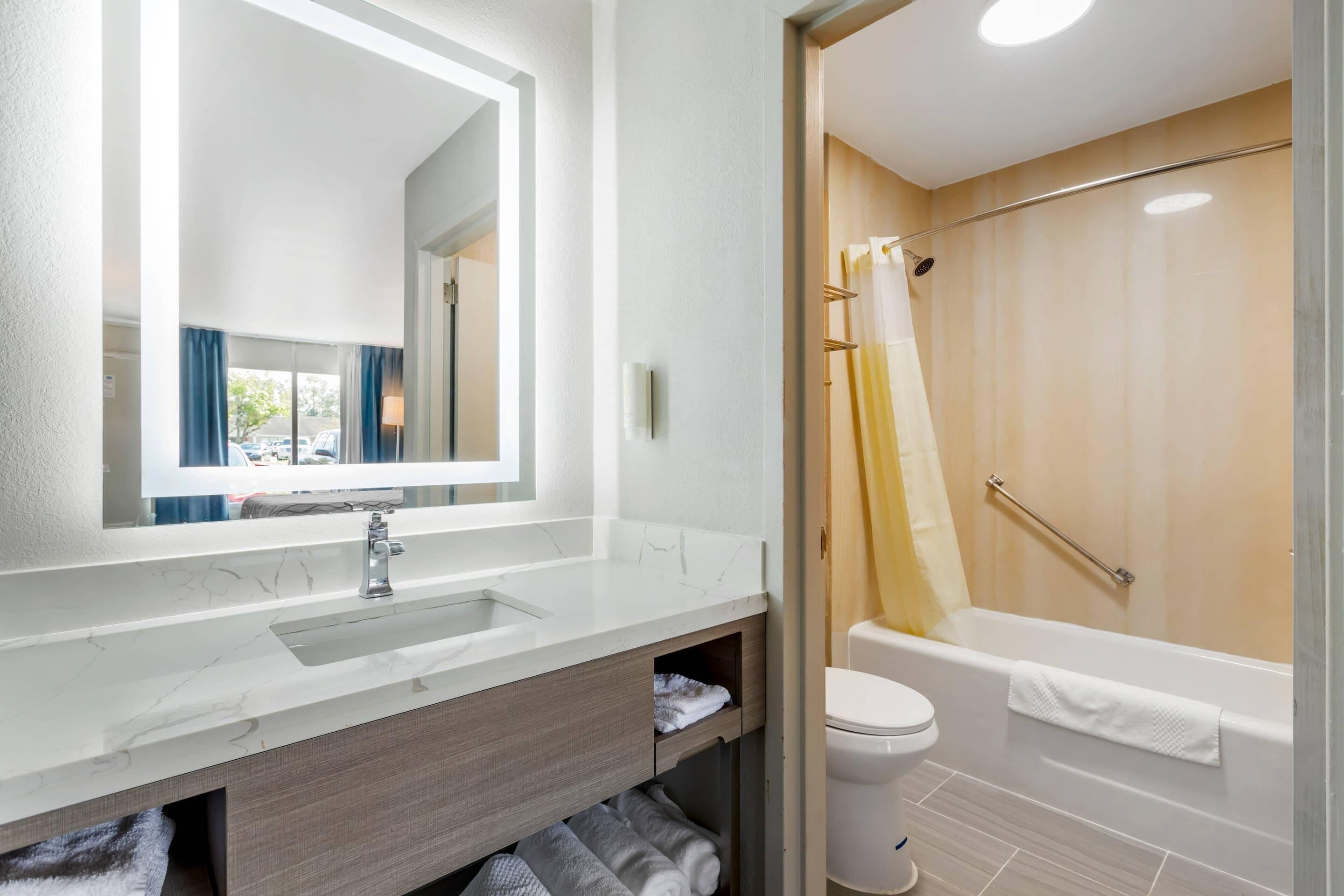 Un baño con lavamanos, espejo y bañera blancos.