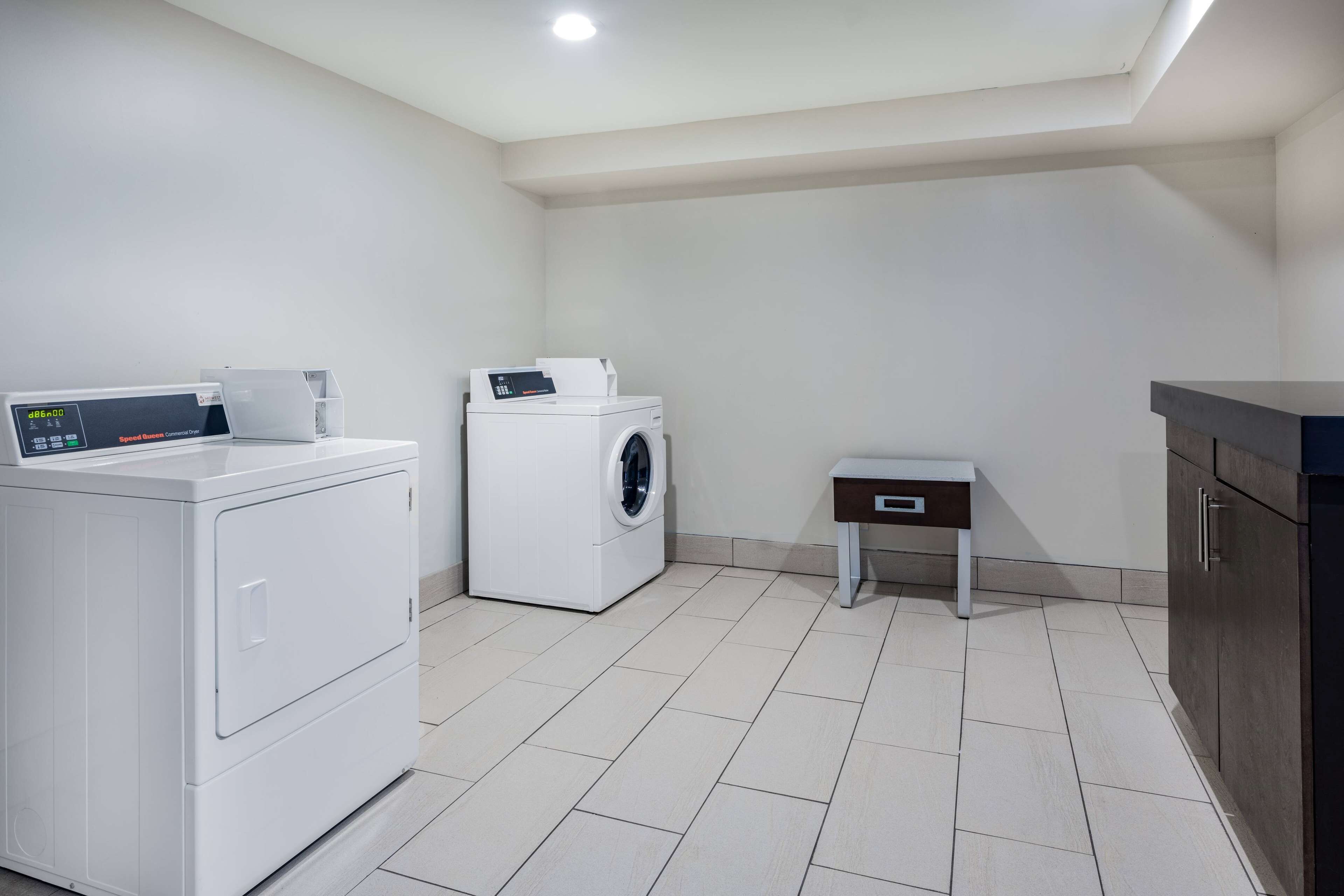 A laundry room with a front-loading washer and dryer, a small table, and a cabinet.