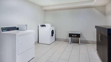 Een wasruimte met een voorlader wasmachine en droger, een klein tafeltje en een kast.
