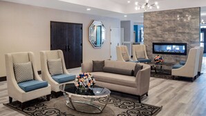 A modern living room with a sofa, two armchairs, a coffee table, and a flat-screen TV. - Wyndham Garden Kenosha Harborside (Kenosha)