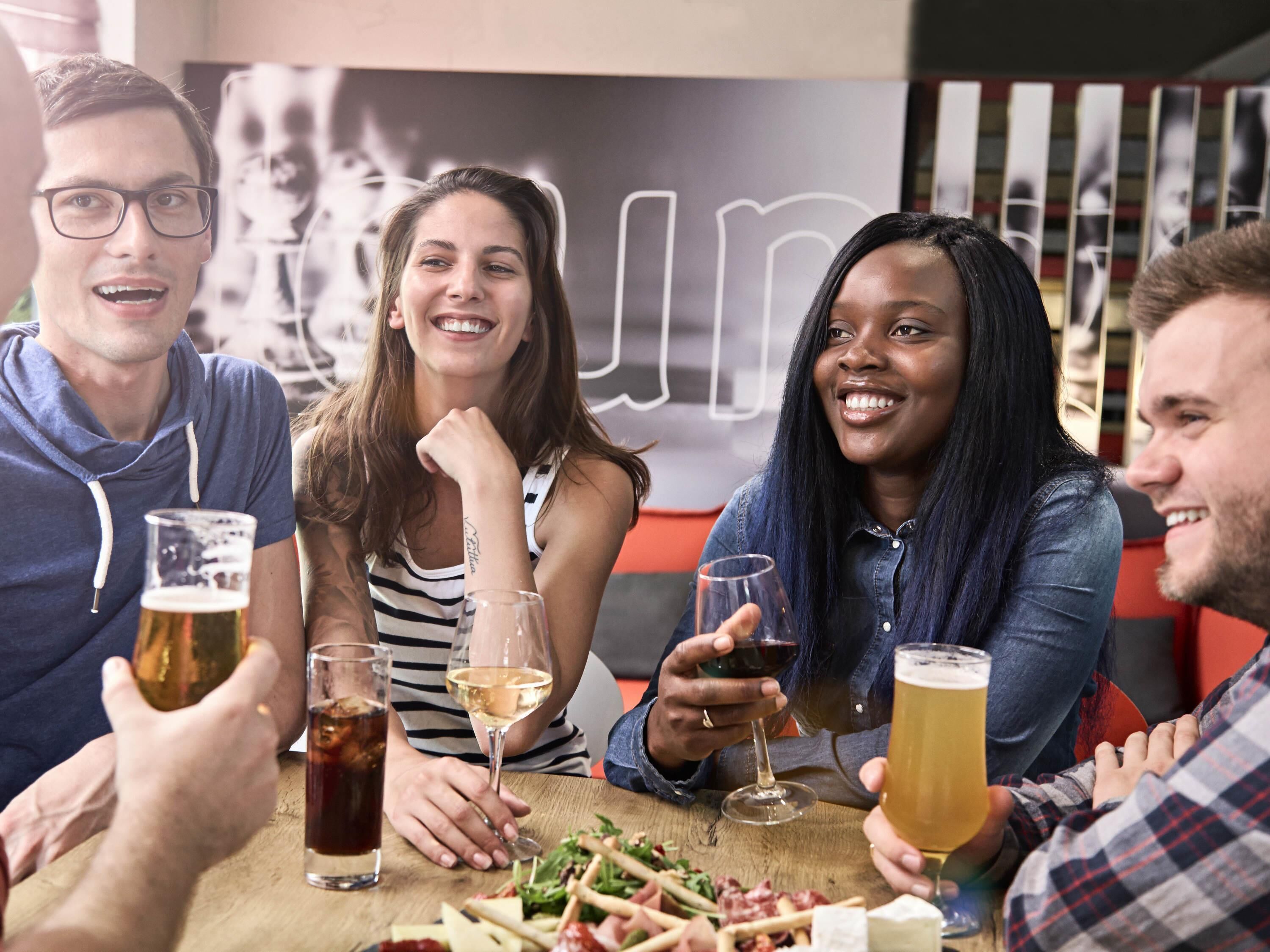 A group of people sitting around a table with drinks and food, in a casual dining setting.