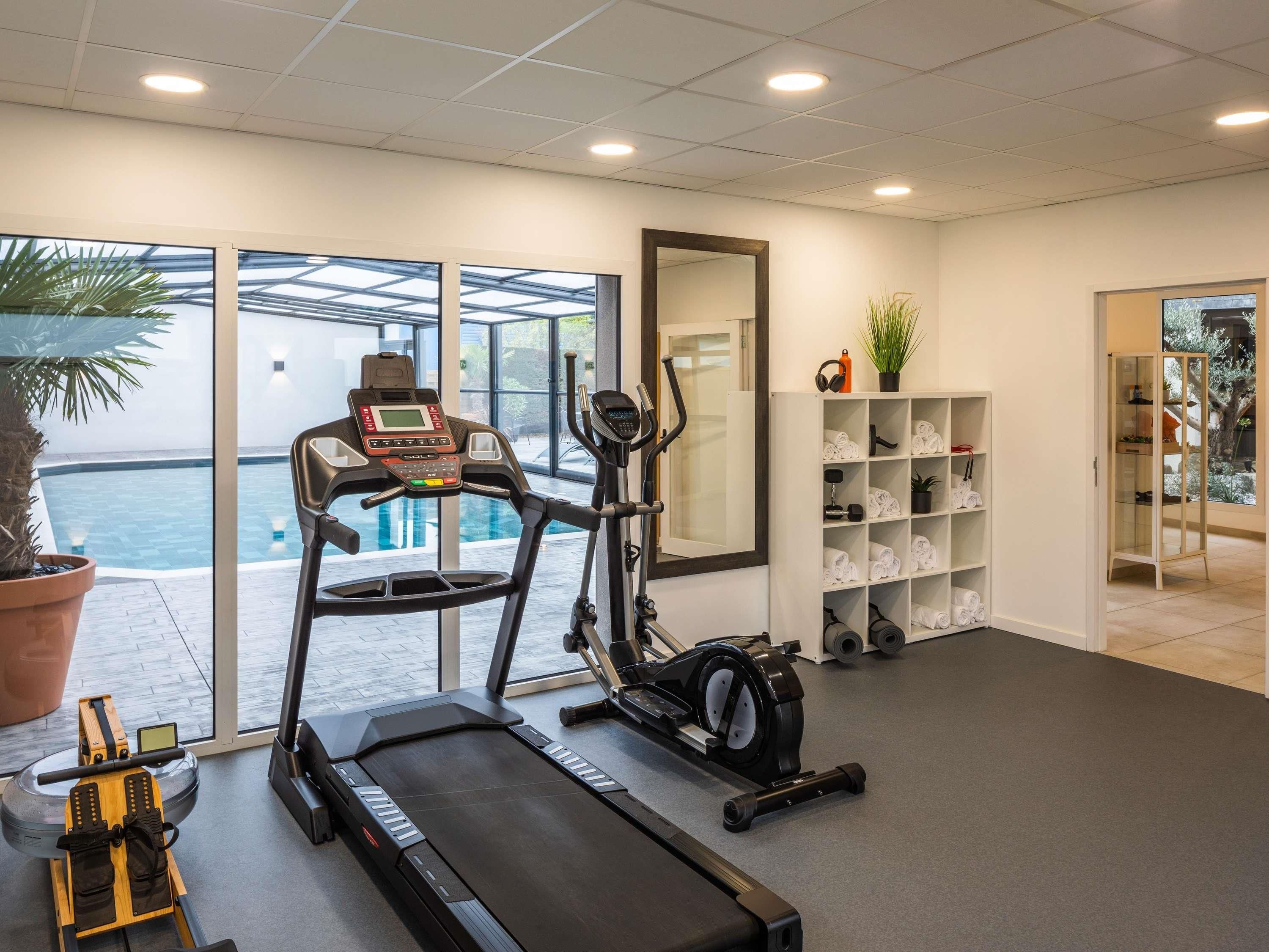A gym with cardio equipment, a treadmill, and a rowing machine.