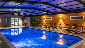 An indoor swimming pool with a checkered floor, lounge chairs, and a wooden wall with a green wall feature.