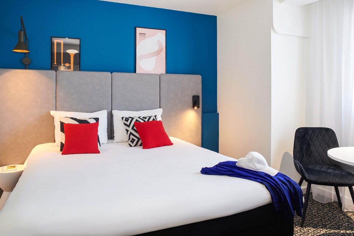 A hotel room with a bed, a desk, and a chair.