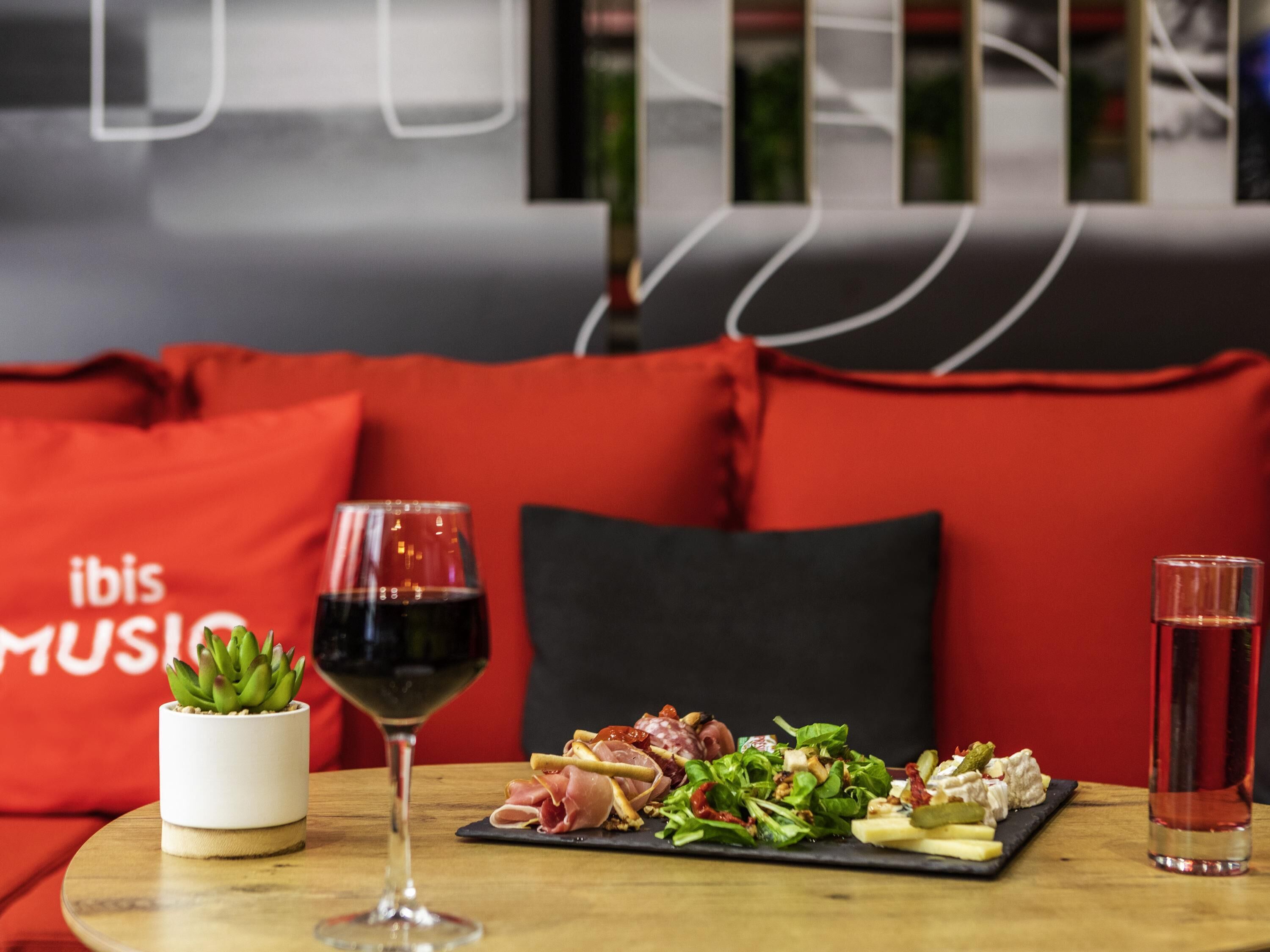 A dining table with a glass of red wine, a plate of appetizers, and a glass of water.