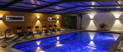 Una piscina con piso a cuadros, rodeada de sillas de descanso y un muro de madera.