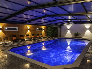 Una piscina con piso a cuadros, rodeada de sillas de descanso y un muro de madera.