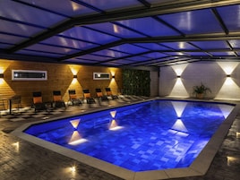 Una piscina con piso a cuadros, rodeada de sillas de descanso y un muro de madera.