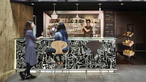 Zona de bar con un menú en pizarra que enumera opciones de comida y bebidas.