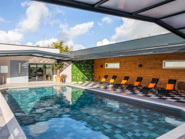 Un área de piscina moderna con piso a cuadros, sillas de descanso y pared de madera.