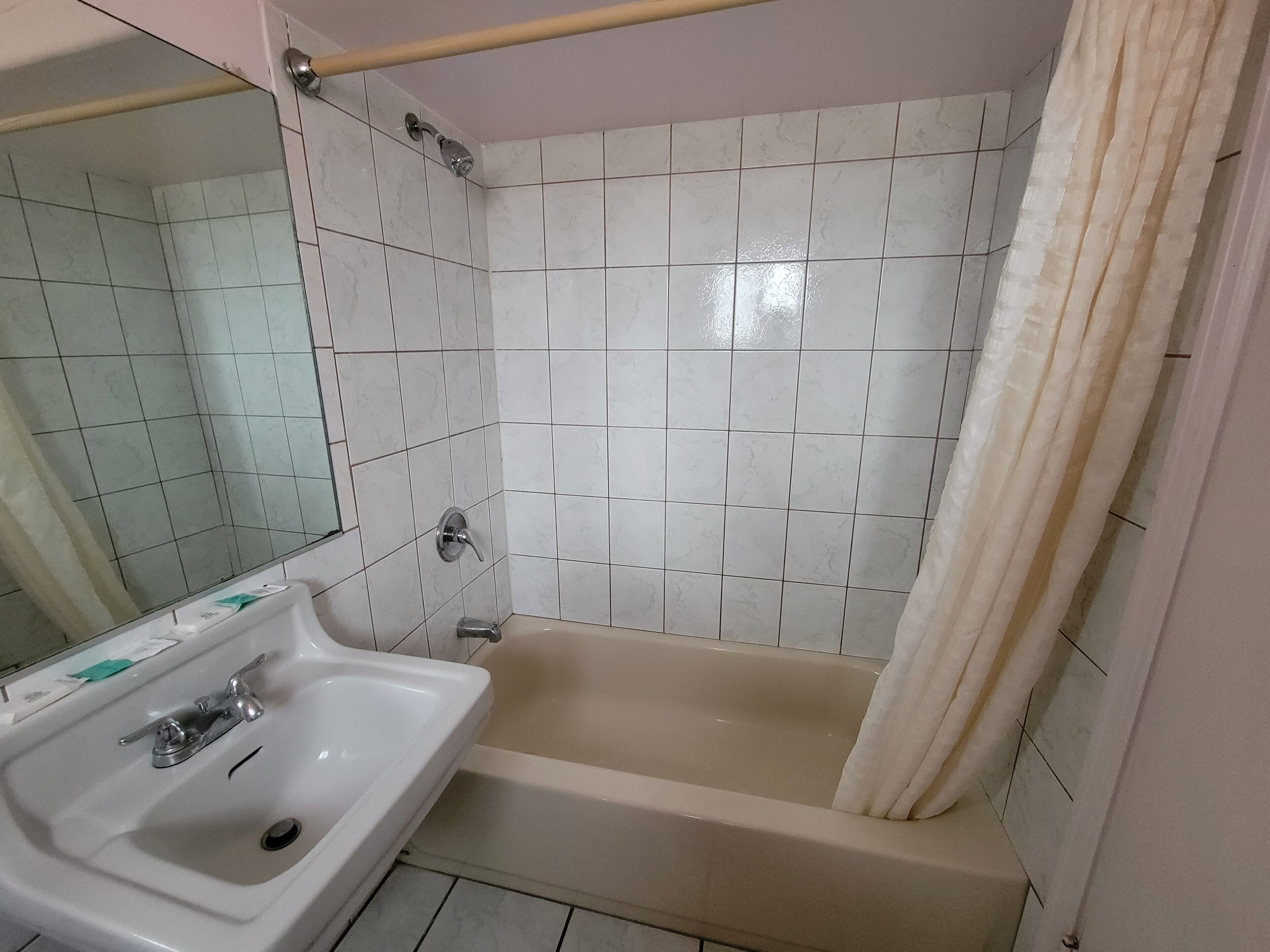 Een badkamer met een wastafel, spiegel, badkuip en betegelde wanden.