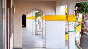 A covered walkway with columns and yellow railings, leading to an arched entrance. - Emerald Inn & Lounge (Blythe)