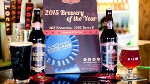 A bar with a sign for the 2015 Brewery of the Year, various beer bottles, and a glass of beer. - Emerald Inn & Lounge (Blythe)