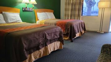 Una habitación de hotel con dos camas, paredes verdes, una ventana con cortinas y una lámpara de pie.