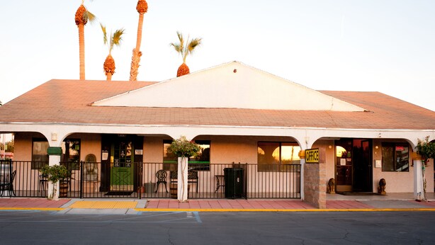 A building with a flat roof, multiple doors, and a sign indicating an office. - Emerald Inn & Lounge (Blythe)