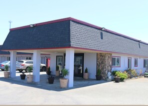 A motel with a red roof, a Coca-Cola sign, and several potted plants in front.