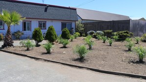 Um imóvel residencial com área de jardim, uma casa com telhado vermelho e um trecho cercado.