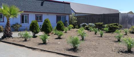 Una propiedad residencial con jardín, una casa de techo rojo y una sección cercada.