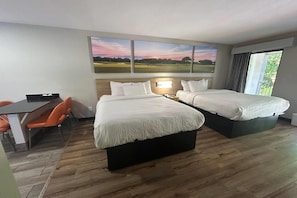 Hotellihuone, jossa on kaksi sänkyä, työpöytä ja tuoli.