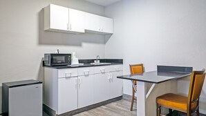 A compact kitchen with white cabinets, a microwave, a coffee maker, and a small refrigerator. - Days Inn by Wyndham Augusta / Fort Eisenhower (Augusta)