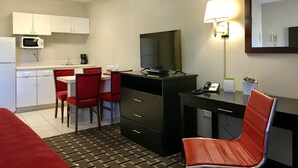 A hotel room with a kitchenette, a desk with a chair, a bed, and a large mirror. - Days Inn by Wyndham Augusta / Fort Eisenhower (Augusta)