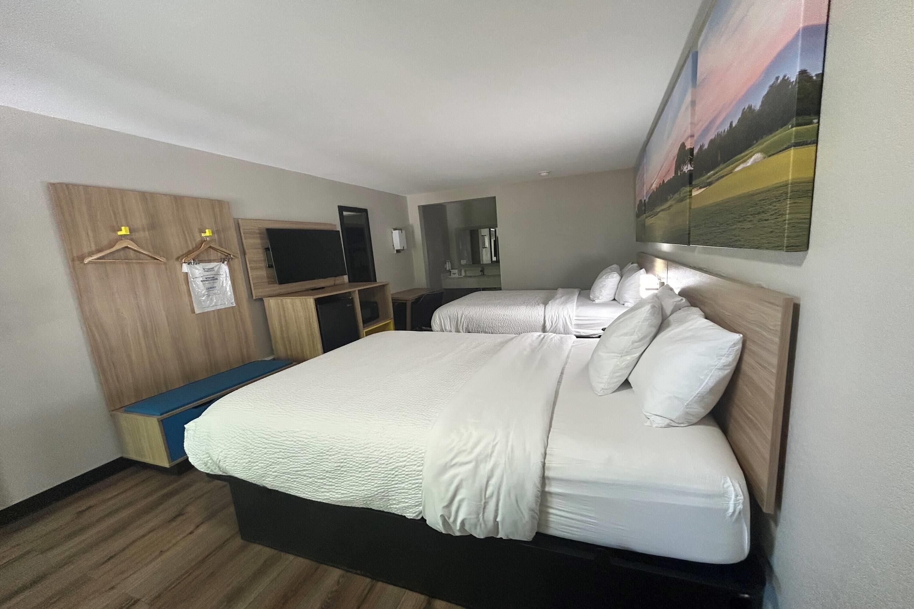 Une chambre d’hôtel avec un grand lit, un bureau avec un ordinateur, une télévision et un tableau au mur.