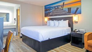 A hotel room with a large bed, a desk with a telephone, and a painting of a pier on the wall. - Days Inn by Wyndham Augusta / Fort Eisenhower (Augusta)