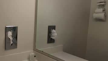 Un baño con un espejo grande, un lavamanos y un perchero para toallas.