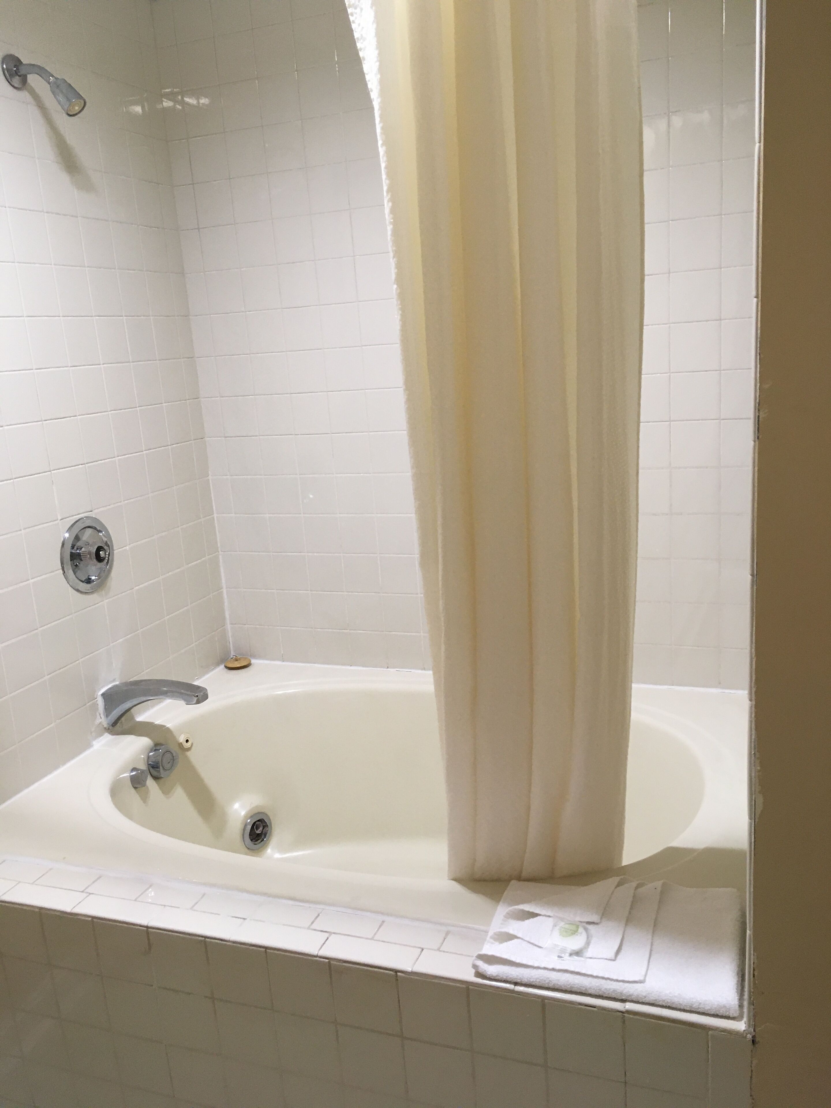 A bathroom with a bathtub, a showerhead, and a towel rack.