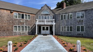 A two-story building with a central entrance, a small balcony, and a pathway leading to the entrance.