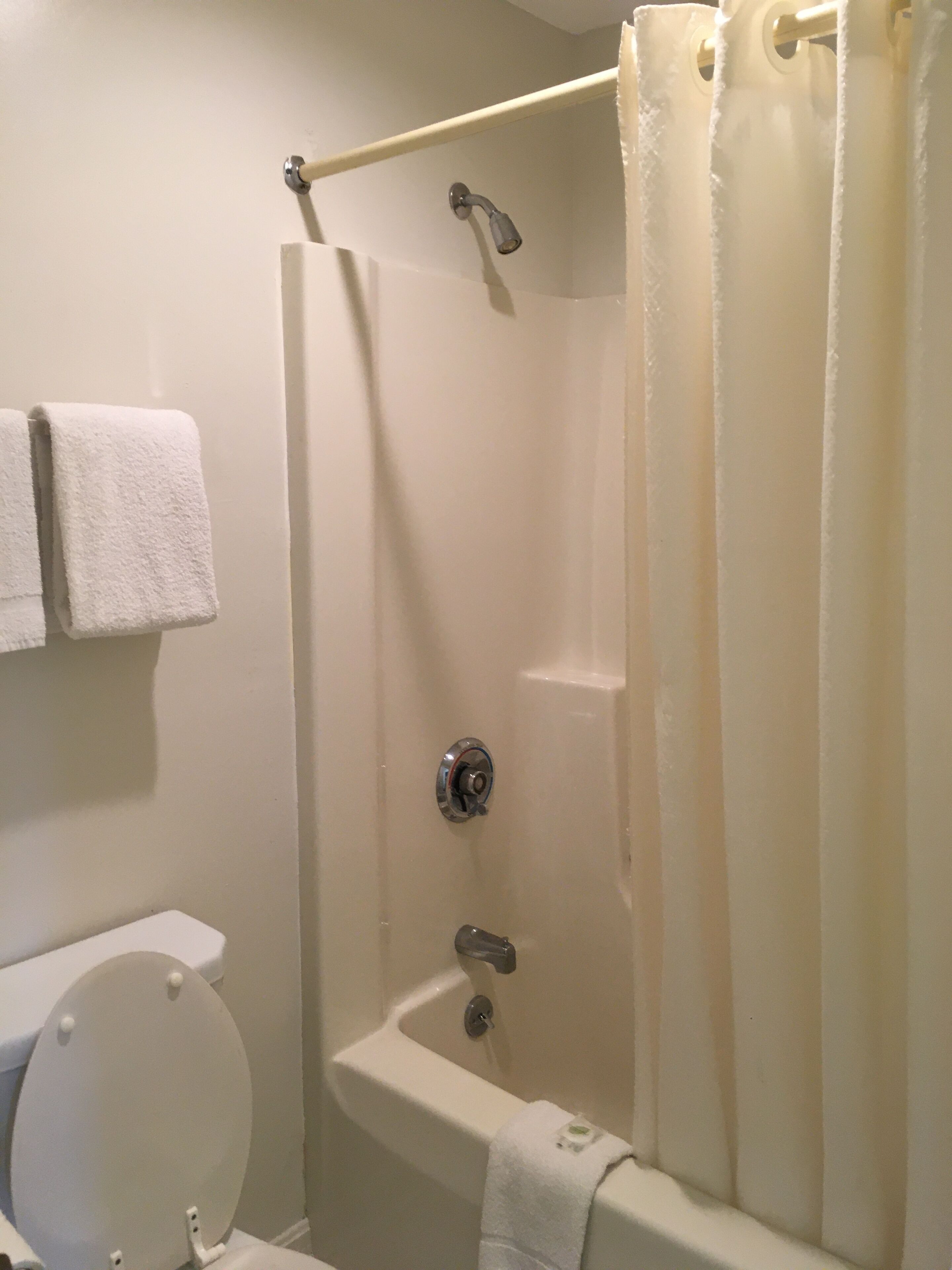 Une salle de bain équipée d’une baignoire, d’une douche, de toilettes et de deux serviettes accrochées au mur.