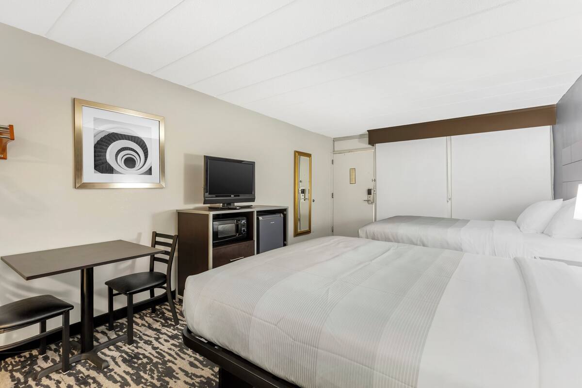 A hotel room with a bed, a desk with a chair, a television, and a microwave.