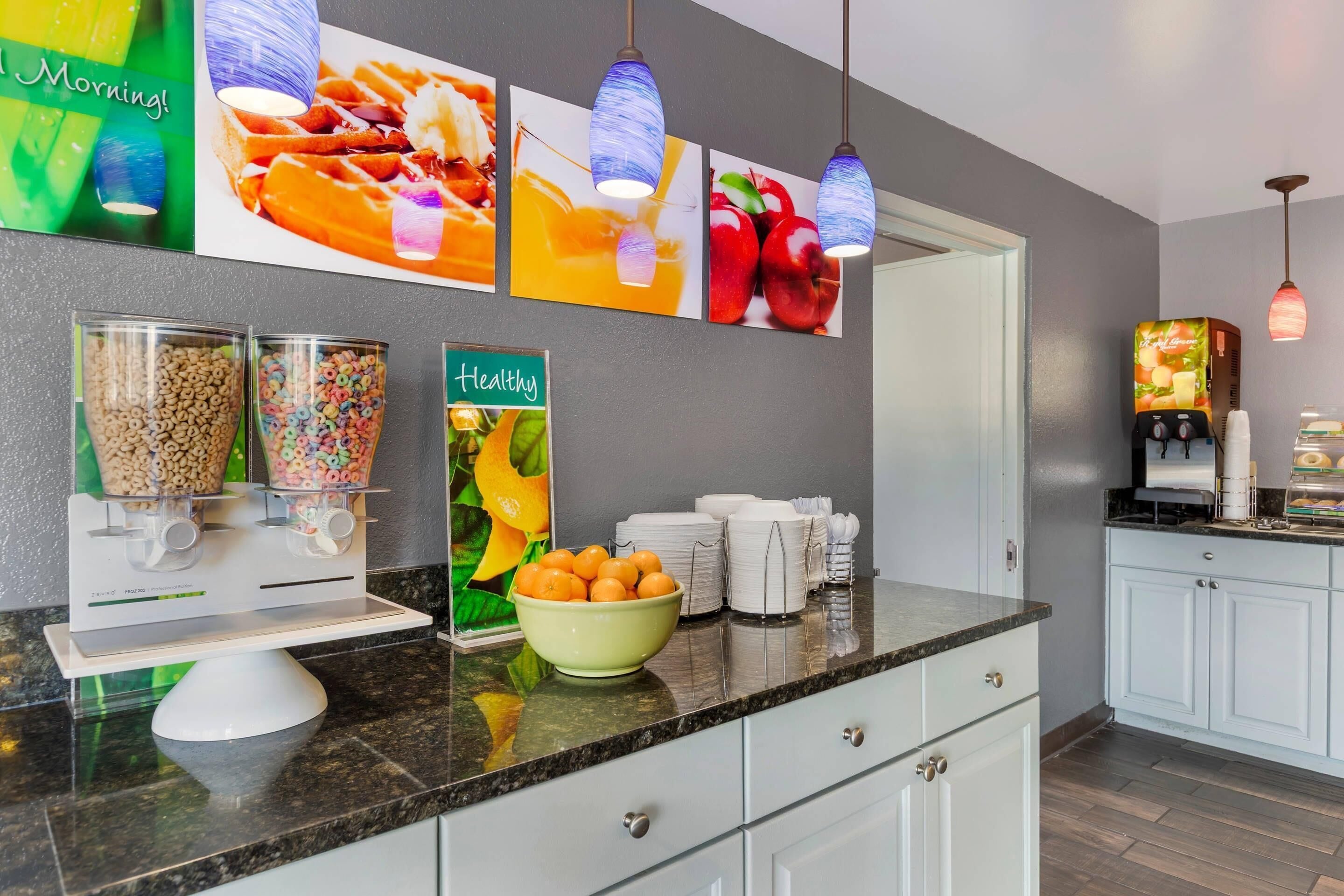 A breakfast bar with cereal dispensers, a bowl of oranges, and a 'healthy' sign.