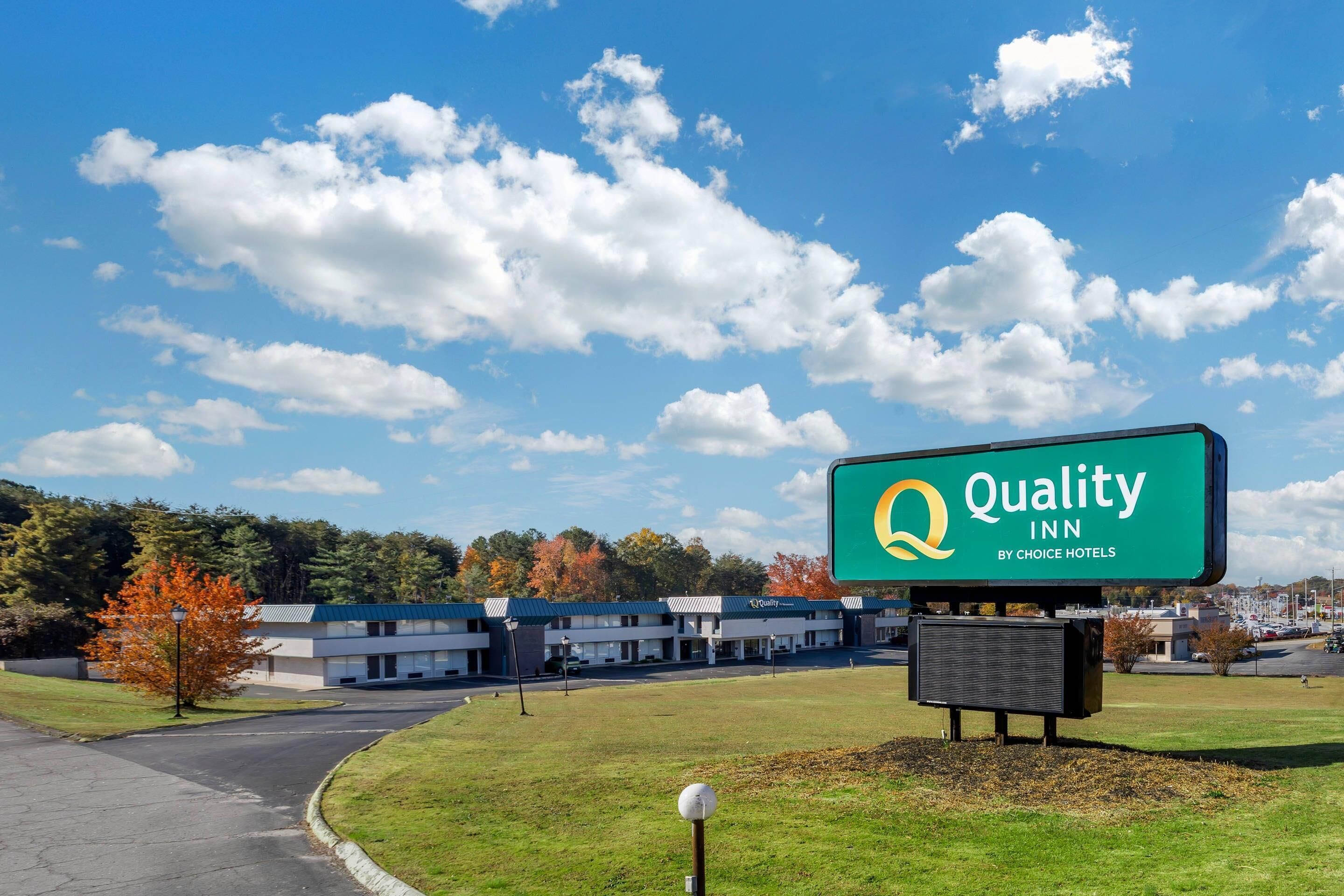 Uma Quality Inn by Choice Hotels com céu claro e folhagem outonal ao fundo.