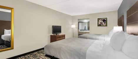 A hotel room with two beds, a TV, a mirror, and a painting on the wall.