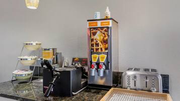 A kitchenette with a waffle maker, toaster, and waffle dispenser.